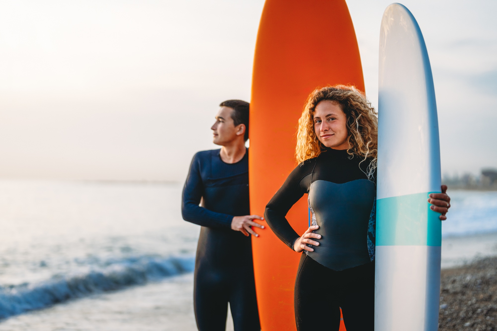 Two friends surfers going for surfing in the sea. Carrying surfboards running in to the sea surfing