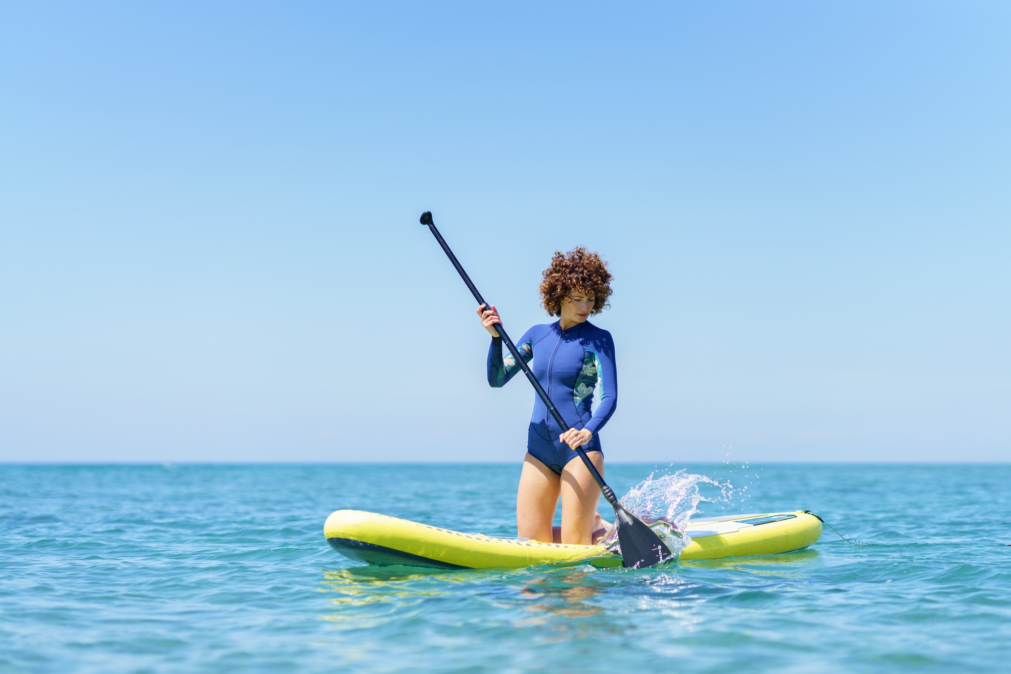 Woman with paddle on paddleboard in sea