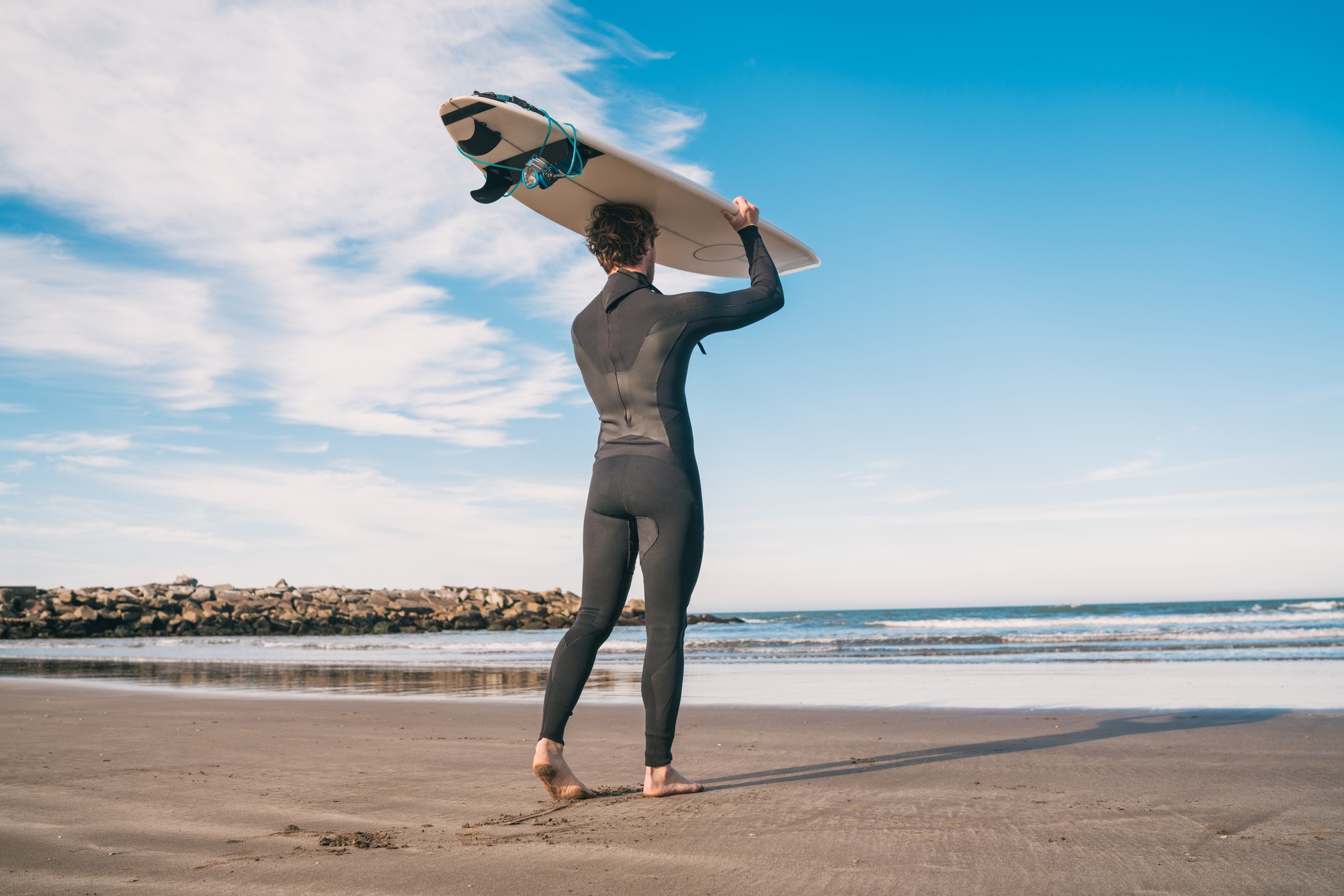 Young surfer holding up his surfboard.